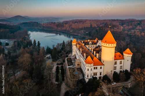 Aerial view of Konopiste,Czech fairytale castle.Picturesque autumn landscape at sunrise with impressive historical monument.Czech tourist attraction.Medieval residence surrounded by forest and pond photo