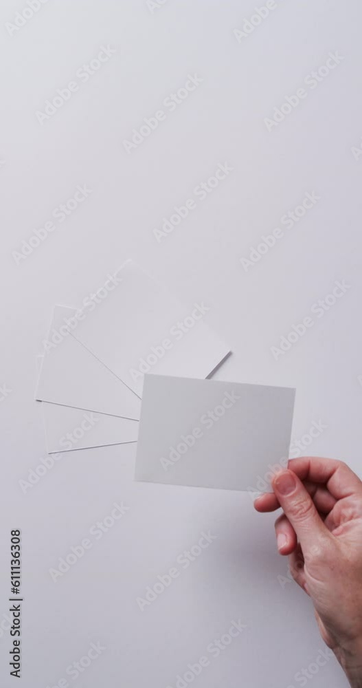 Vertical video of hand holding piece of paper over pieces of paper with copy space in slow motion Vertical video of hand holding piece of paper over pieces of paper with copy space in slow motion