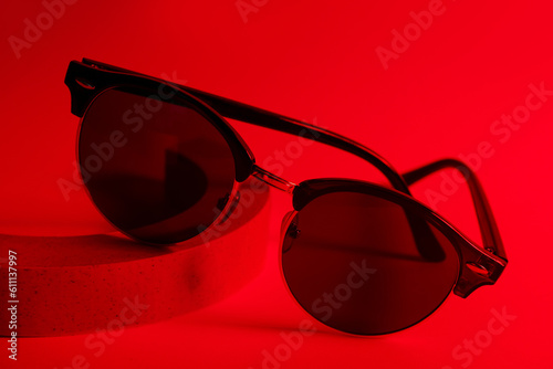 Podium with stylish sunglasses on red background