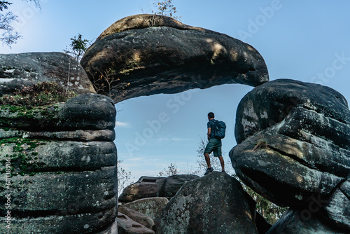 Man backpacker in Rock Gate in nature reserve Broumov Walls, Czech Republic.Old sandstone rock formation in Broumovske steny.Active male traveler standing on rock enjoying views,success, adventure photo