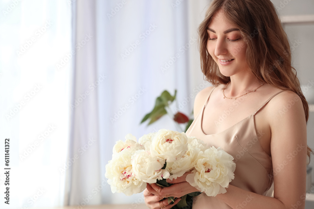Beautiful young woman with bouquet of peony flowers in kitchen Beautiful young woman with bouquet of peony flowers in kitchen