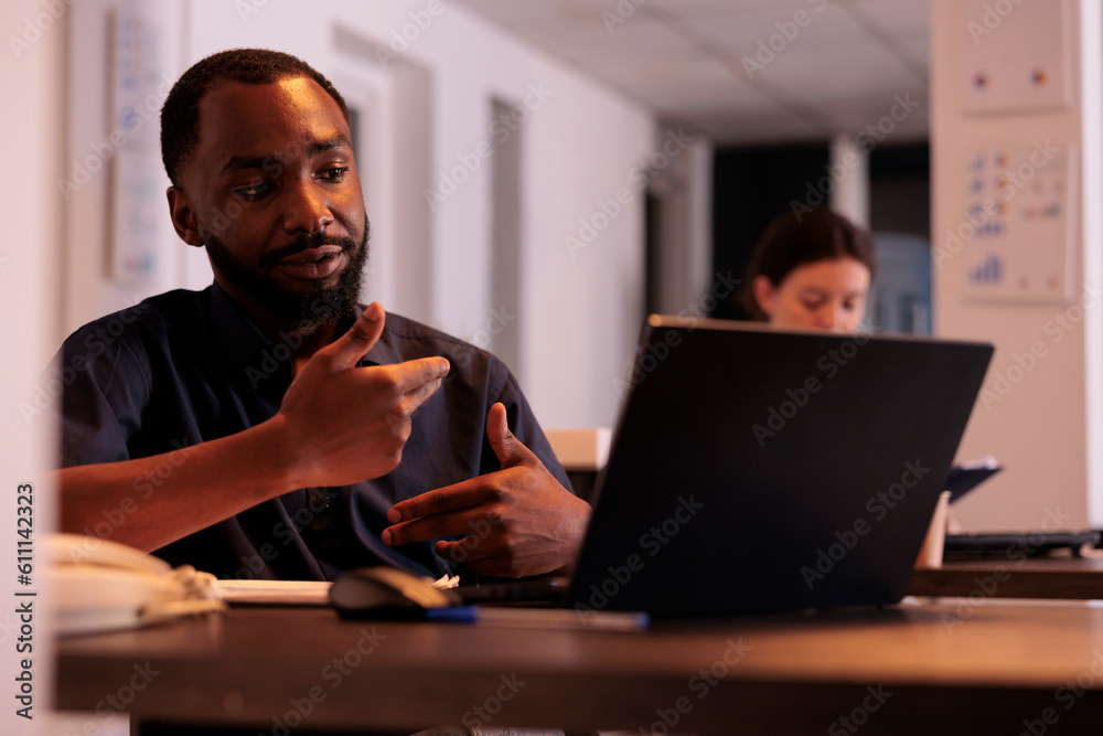 Project manager discussing company strategy plan on videoconference with coworker, corporate worker answering internet call in office at night. African american man using videocall computer software Project manager discussing company strategy plan on videoconference with coworker, corporate worker answering internet call in office at night. African american man using videocall computer software