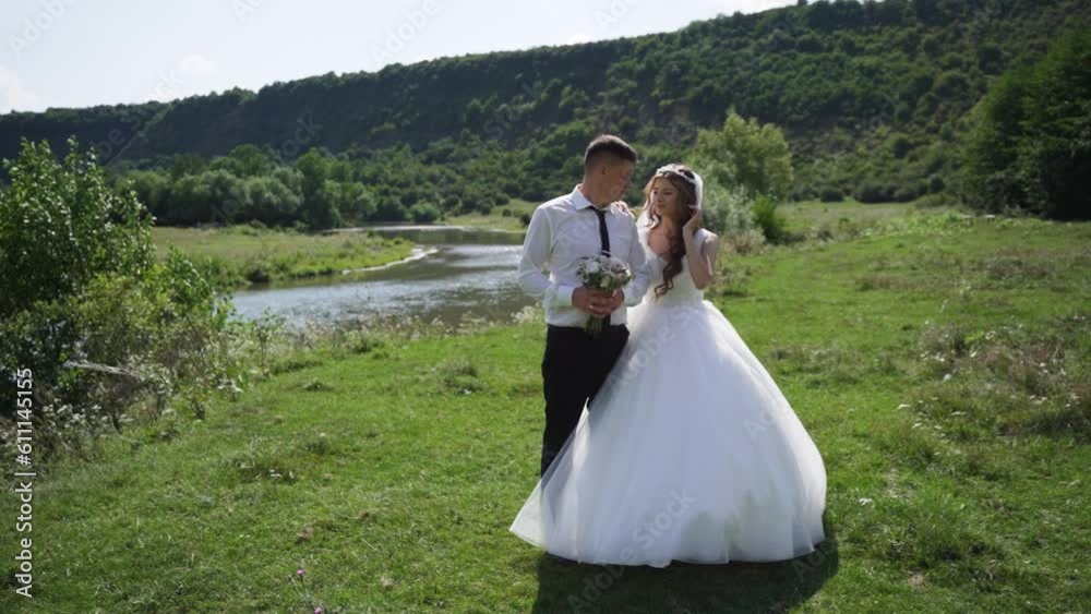 Happy couple newlyweds smiling and walking on the shore of the river. Steadyshot Happy couple newlyweds smiling and walking on the shore of the river. Steadyshot