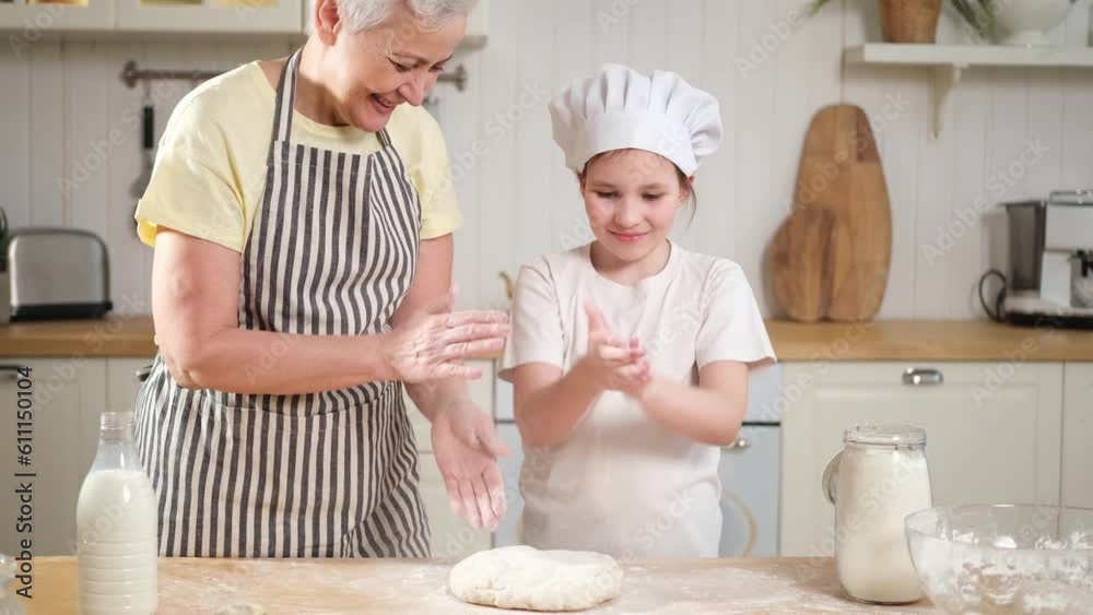 Happy family in kitchen. Kid girl grandma have fun playing clap hands with flour cooks bake cookies. Grandmother granddaughter child knead dough in kitchen. Teamwork helping family generations