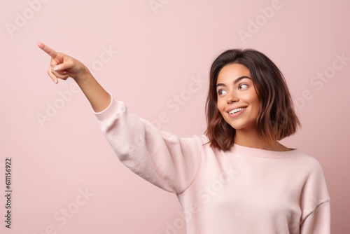 Environmental portrait photography of a satisfied girl in her 30s pointing up against a pastel or soft colors background. With generative AI technology