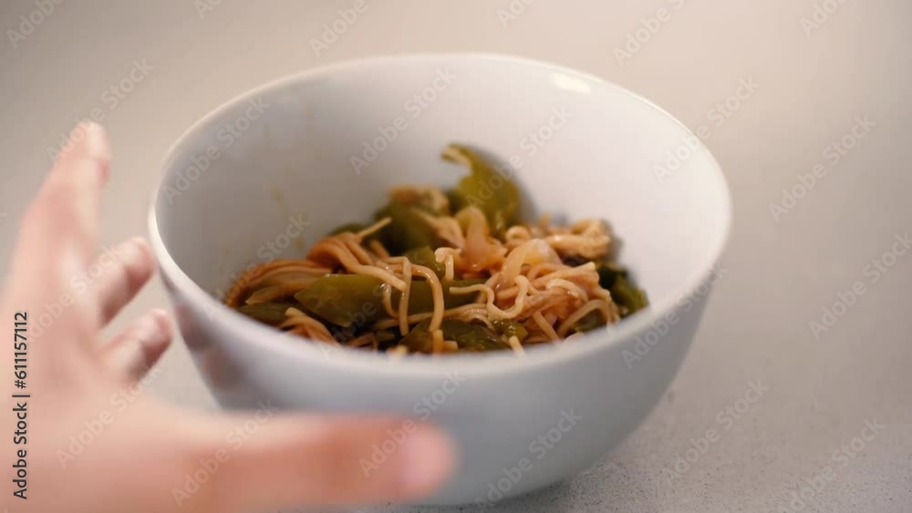 Vista aérea de un bol con noodles y pimientos verdes. Moviendo los fideos con un tenedor. Comida asiática. Vista aérea de un bol con noodles y pimientos verdes. Moviendo los fideos con un tenedor. Comida asiática.