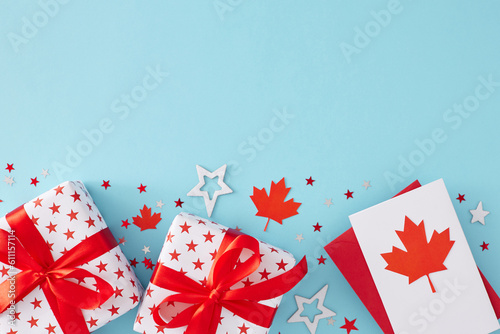 Happy Victoria day concept. Top view flat lay of gift boxes in national colors, postcard with red maple leaf and stars shaped confetti on light blue background with blank space for text or promotion