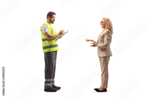 Road assistance worker in a reflective vest writing a document and talking to a woman