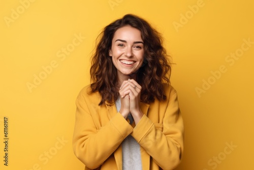 Photography in the style of pensive portraiture of a grinning girl in her 20s making an ok gesture with the fingers against a pastel yellow background. With generative AI technology