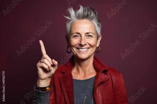 Close-up portrait photography of a glad mature woman making an ok gesture with the fingers against a rich maroon background. With generative AI technology