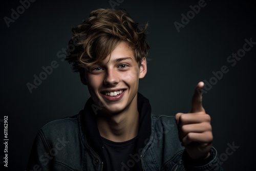 Close-up portrait photography of a happy boy in his 20s raising a finger as if having an idea against a dark grey background. With generative AI technology