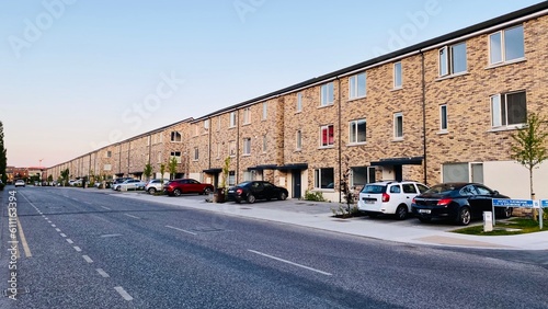 Identical private houses. Houses in Ireland, abroad. Houses near the road, on the carriageway. Parked cars near houses.