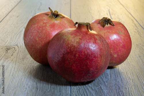 Three fresh ripe pomegranates on a gray wooden table. Close-up