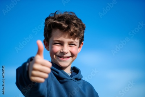 Photography in the style of pensive portraiture of a grinning boy in his 30s showing a thumb up against a sky-blue background. With generative AI technology