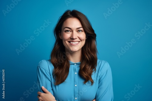 Medium shot portrait photography of a grinning girl in her 30s crossing the arms against a cerulean blue background. With generative AI technology