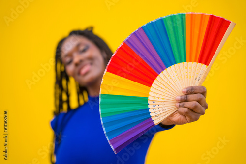 Lgbt rainbow fan and an attractive black ethnic woman on a yellow background