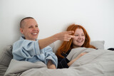 Two happy laughing lisbian women watching tv in bed. Joyful interaction, relaxation.