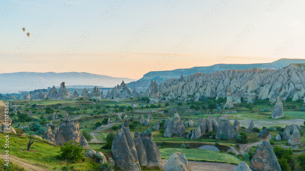 Fototapeta premium Cappadocia Turkey. Hot air balloons flying over fairy chimneys at sunrise in Cappadocia. Travel to Turkey. Touristic landmarks of Turkiye. Selective focus included.