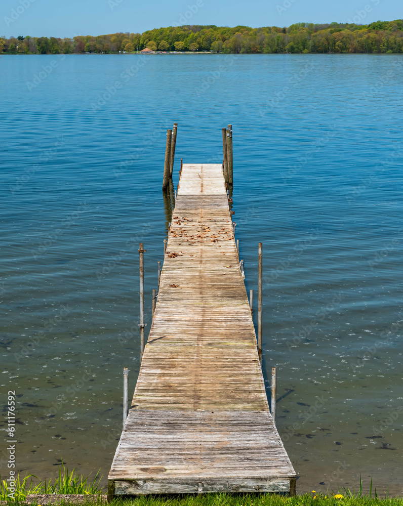 Obraz premium A wooden pier into Lake Chautauqua in Beemus Point, New York, USA on a sunny spring day