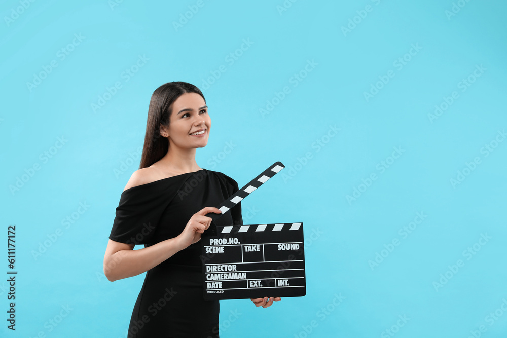 Happy actress with clapperboard on light blue background, space for text. Film industry