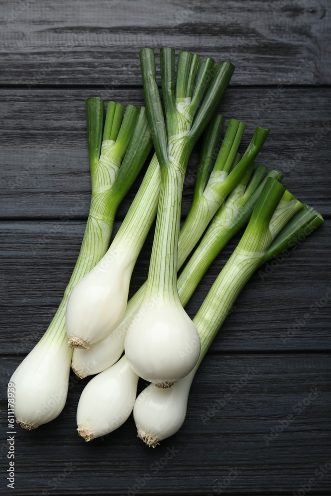 Whole green spring onions on black wooden table, flat lay Whole green spring onions on black wooden table, flat lay