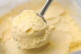 Taking scoop of vanilla ice cream from container, closeup