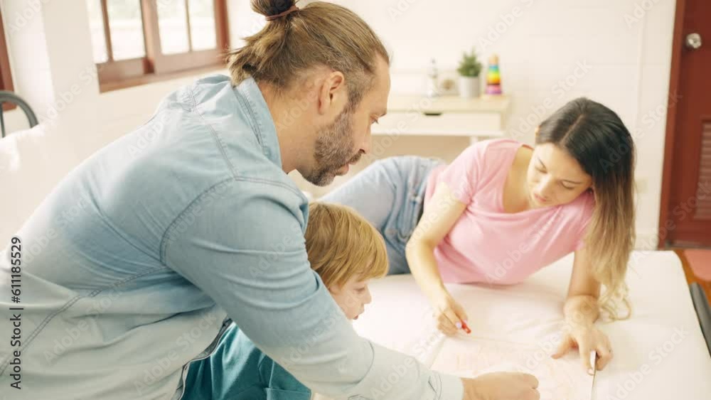 Happy family Caucasian father and mother teach little baby son drawing and coloring on paper on the bed in bedroom. Parents and child boy kid enjoy and fun indoors activity lifestyle together at home. Happy family Caucasian father and mother teach little baby son drawing and coloring on paper on the bed in bedroom. Parents and child boy kid enjoy and fun indoors activity lifestyle together at home.