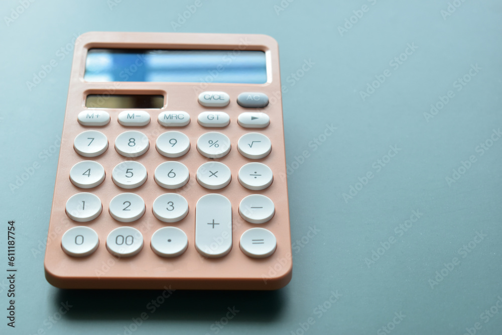 close up modern peach colour pastel calculator and white button on blue background, business and finance accounting concept close up modern peach colour pastel calculator and white button on blue background, business and finance accounting concept