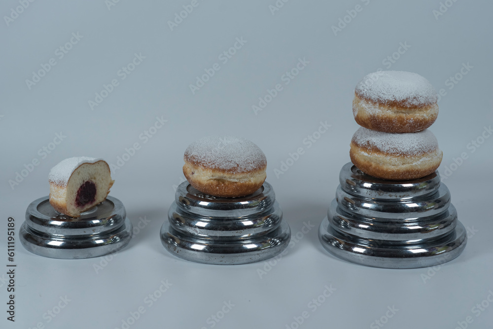 Fototapeta premium pączki z cukrem pudrem. Odważniki z siłowni do ćwiczenia. Bilans kaloryczny.