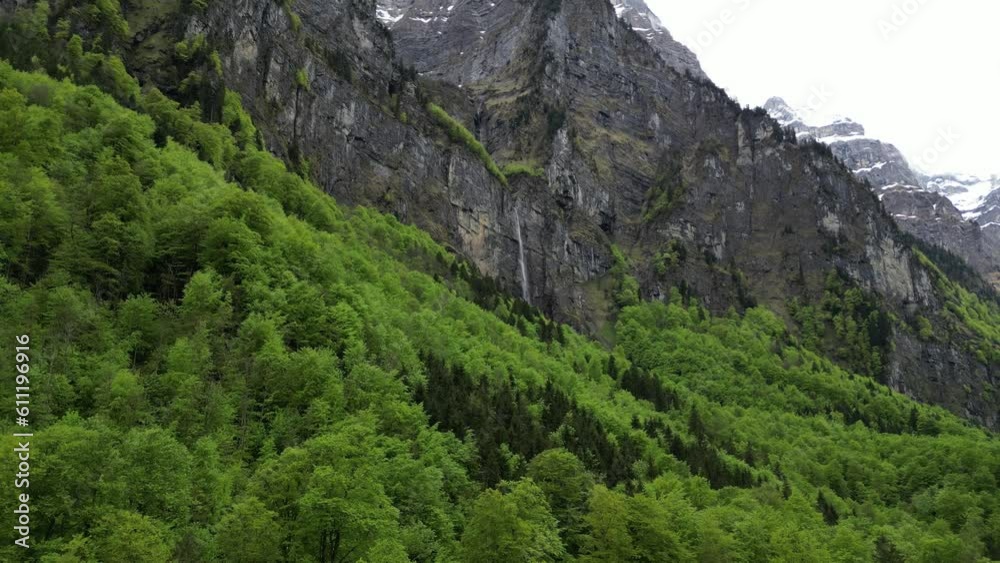 Beautiful aerial shot of waterfall nestled in rocky mountain, Alpine forest