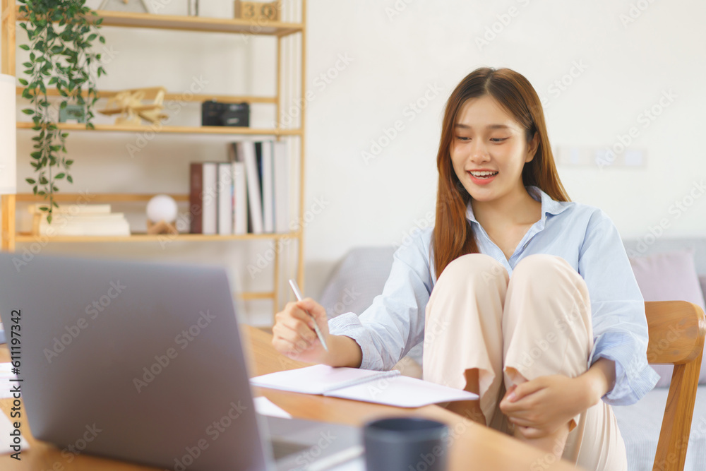 Business at home concept, Businesswoman sits with knees up on chair to reading data and taking note Business at home concept, Businesswoman sits with knees up on chair to reading data and taking note
