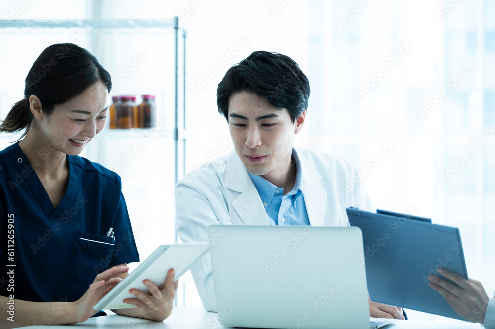 Doctors having a meeting while looking at electronic tablets and materials Doctors having a meeting while looking at electronic tablets and materials