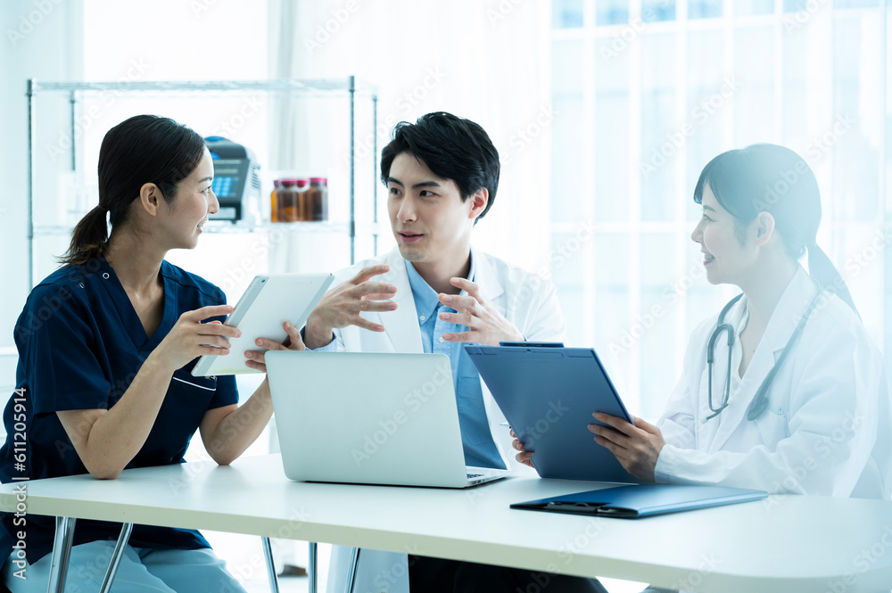Doctors having a meeting while looking at electronic tablets and materials Doctors having a meeting while looking at electronic tablets and materials