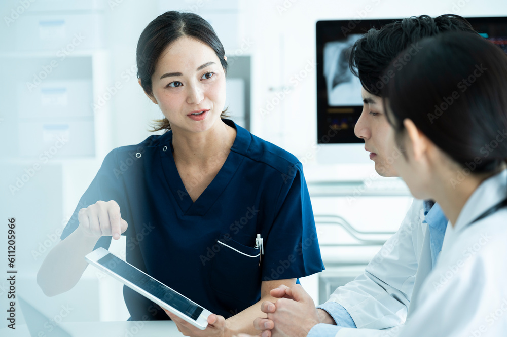 Doctors having a meeting while looking at electronic tablets and materials Doctors having a meeting while looking at electronic tablets and materials