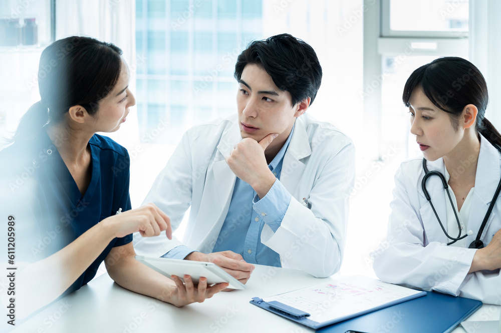 Doctors having a meeting while looking at electronic tablets and materials Doctors having a meeting while looking at electronic tablets and materials