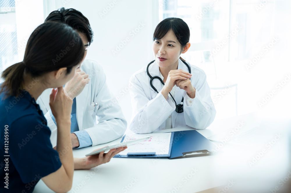 Doctors having a meeting while looking at electronic tablets and materials Doctors having a meeting while looking at electronic tablets and materials
