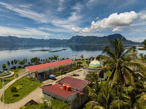 Lake Maninjau with a mosque on the shore through a palm tree. Sumatra, Indonesia. photo