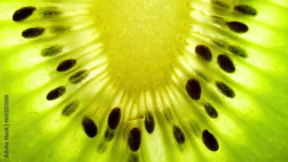 Captivating macro footage of a halved golden kiwi fruit reveals its vibrant green flesh, dotted with tiny black seeds. Juicy and refreshing. Texture and surface background footage. Kiwi background
