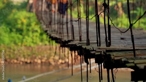 A wooden suspension bridge that sways as people walk on it. Rural scene of Indonesian coruntryside - Low angle shot photo