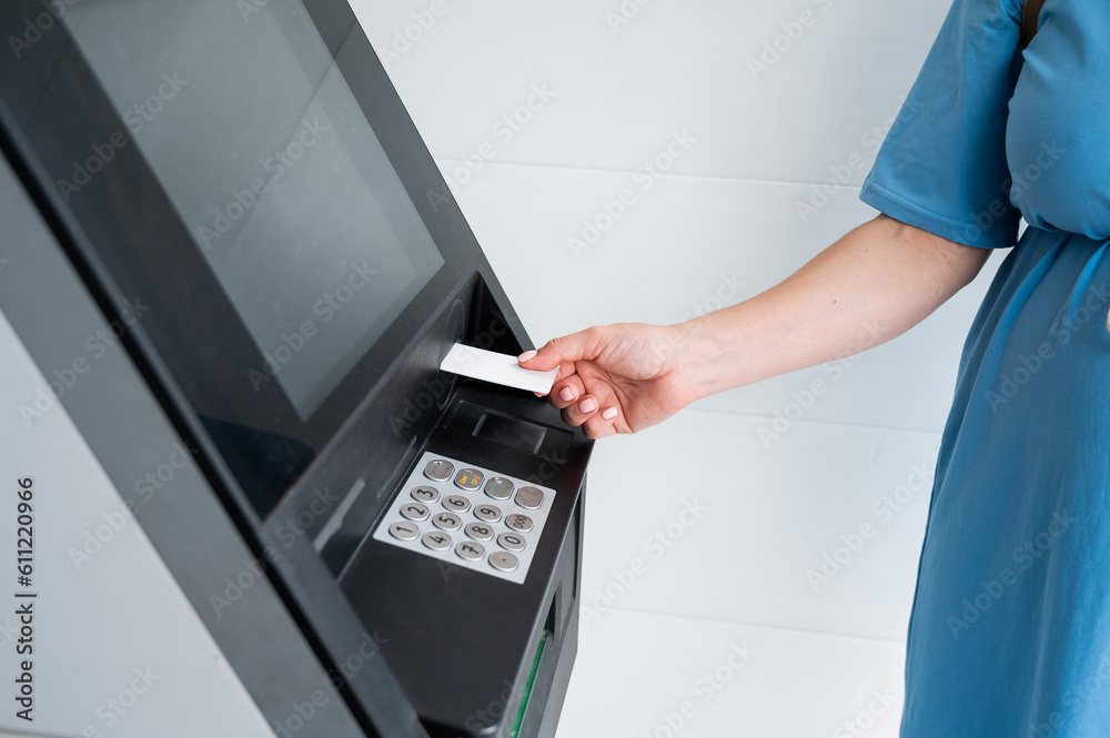 A faceless woman inserts a credit card into an ATM. Close-up of a woman's hands using an ATM machine. A faceless woman inserts a credit card into an ATM. Close-up of a woman's hands using an ATM machine.