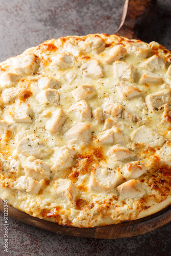 White Cheese Pizza with Chicken closeup on the wooden board on the table. Vertical