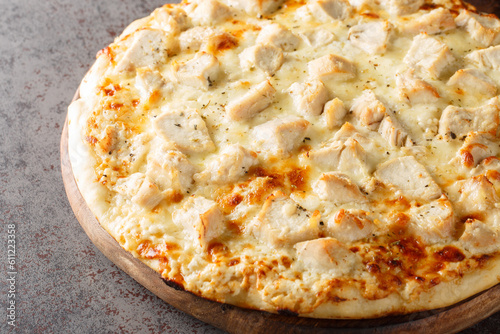 Hot cheese Alfredo pizza with chicken close-up on a wooden board on the table. Horizontal