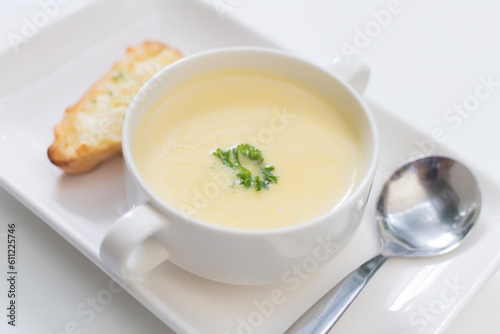 Delicious corn soup In a white bowl served with bread
