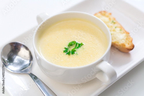 Delicious corn soup In a white bowl served with bread.