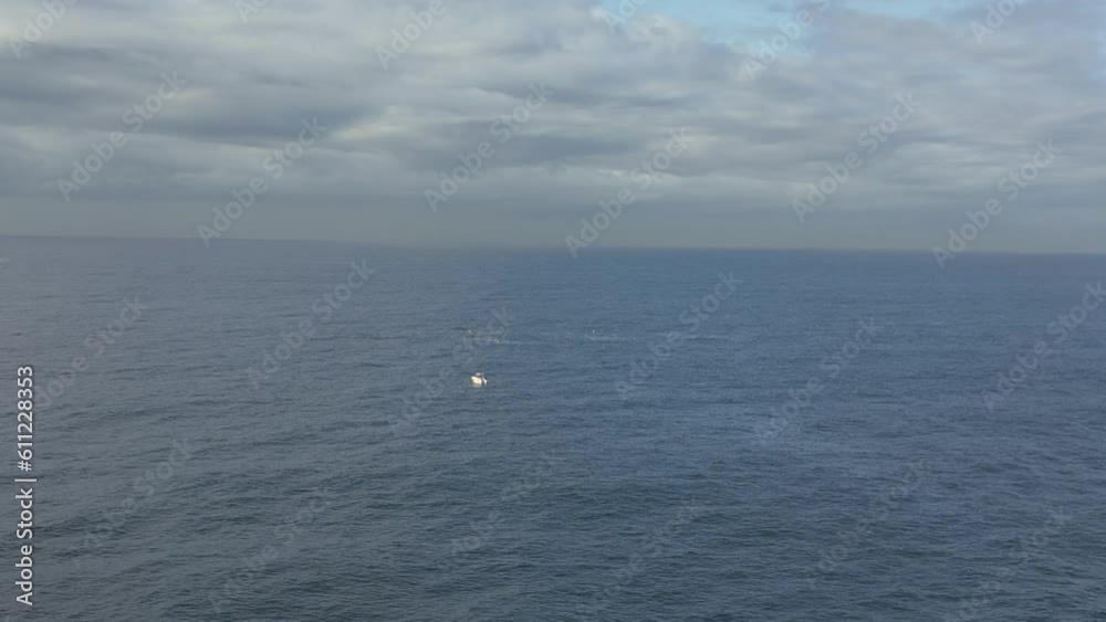 Humpback whale breaches in the distance next to a fishing boat on the ocean. Maroubra Beach, Sydney. Australia. Aerial forward shot. Humpback whale breaches in the distance next to a fishing boat on the ocean. Maroubra Beach, Sydney. Australia. Aerial forward shot.