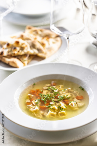 Chicken stock or soup with vegetables and small Italian pasta served on a table