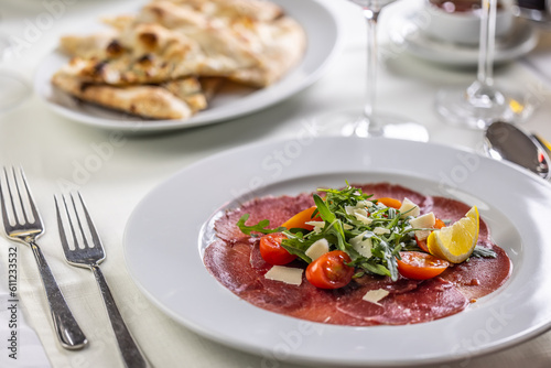 Typical Italian appetizer, carpaccio from veal or beef thinly sliced and served on a plate with salad