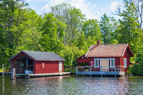 Idyllic red cottage on a lakeshore with a boathouse