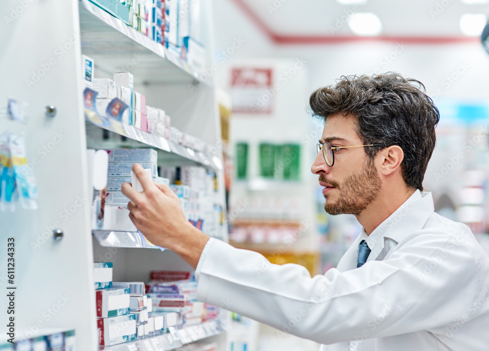 Pharmacist, reading medicine and man in pharmacy while working in store for retail career. Male person in pharmaceutical or medical industry for service, healthcare and inventory check on shelf