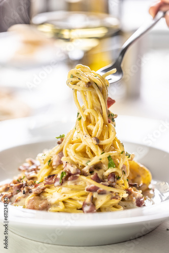Vászonkép Detail of a fork spinning spaghetti carbonara from a full plate